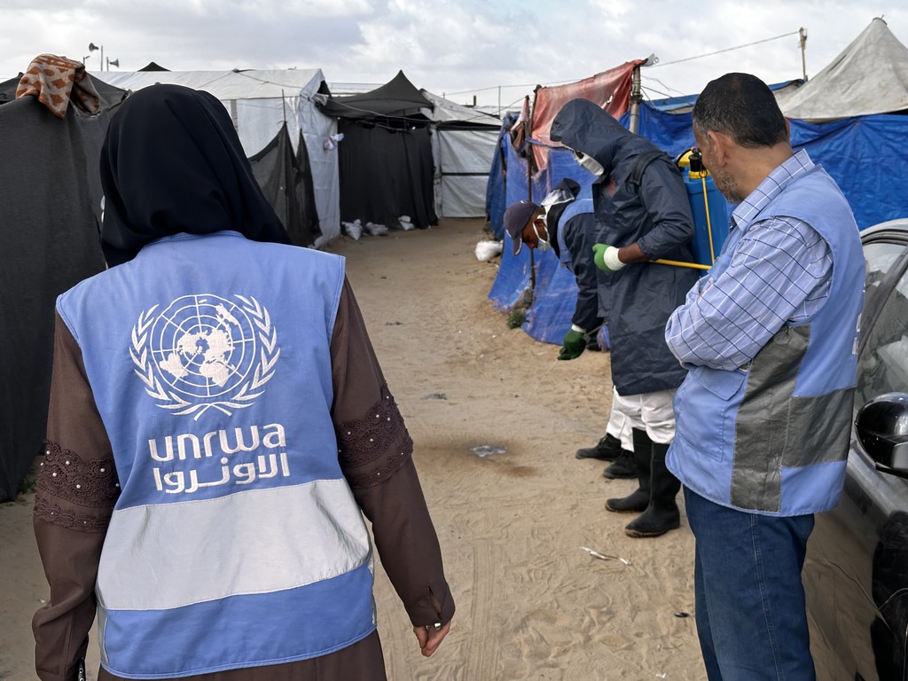 فريق تابع لمكتب صحة البيئة في وكالة الأونروا يقوم برش المبيدات الحشرية في أحد مخيمات النزوح في منطقة المواصي بخان يونس، غزة.